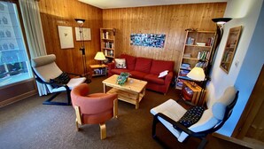 A cozy living room with a red sofa, two armchairs, a coffee table, and a bookshelf. - Pre Vert D62, Morgins (Morgins)