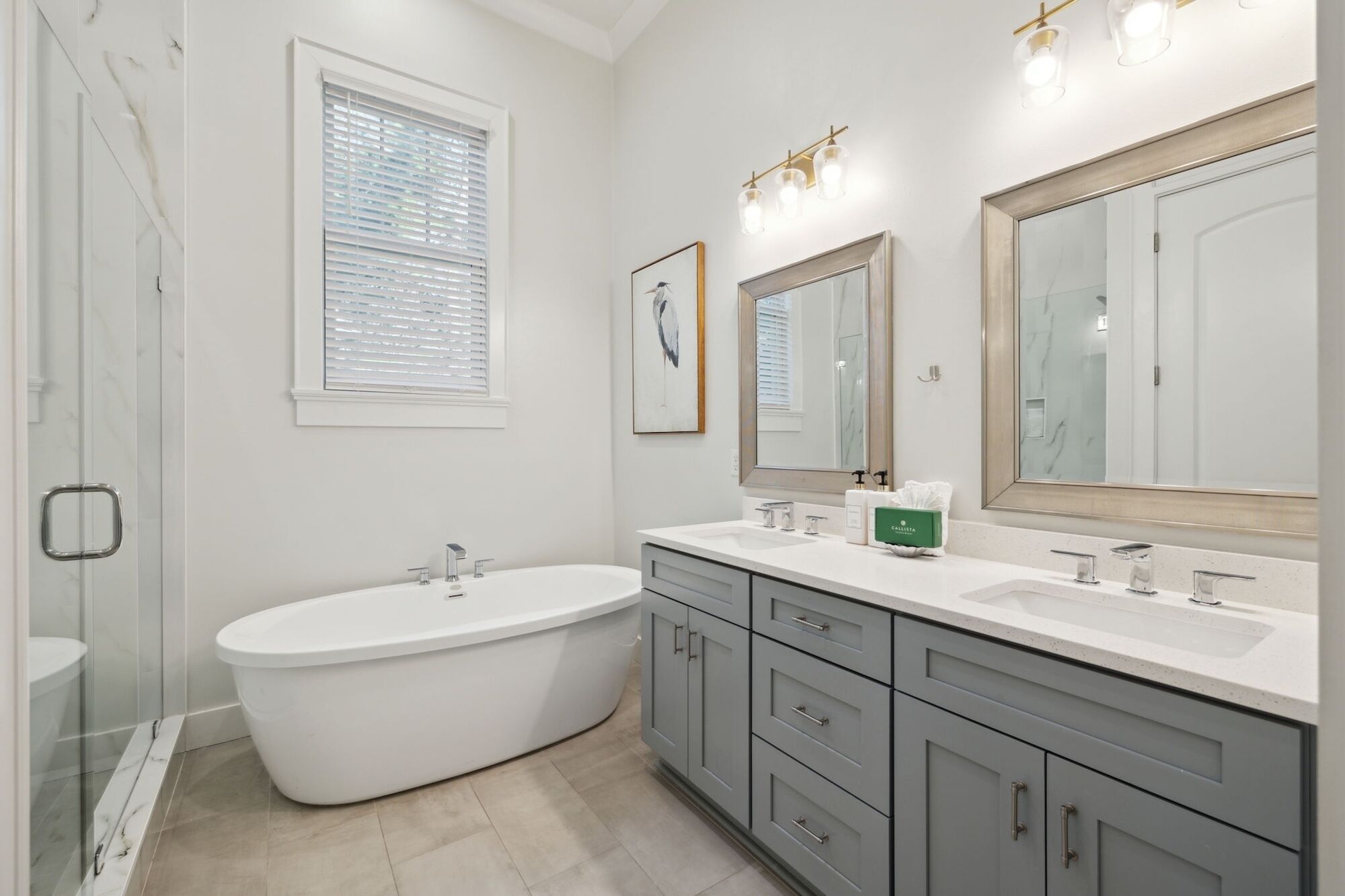 A modern bathroom with a freestanding bathtub, two sinks, and a large mirror.