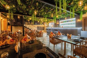 A restaurant with tables set for dining, a bar area, and a staircase leading to an upper level. - Royal Prime - A City Center Botique Hotal in Jaipur (Jaipur)