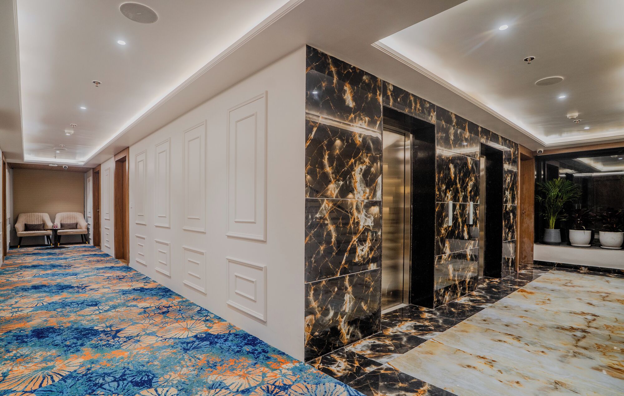 A hotel lobby with a marble floor, a seating area with two sofas, and a reception desk.