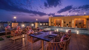 A rooftop dining area with tables and chairs, a pool, and decorative lighting. - Royal Prime - A City Center Botique Hotal in Jaipur (Jaipur)