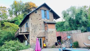 Ein rustikales Steinhaus mit Balkon, einer kleinen Veranda und einem Poolbereich.