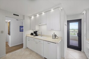 A modern kitchen with white cabinets, a sink, and a coffee maker.