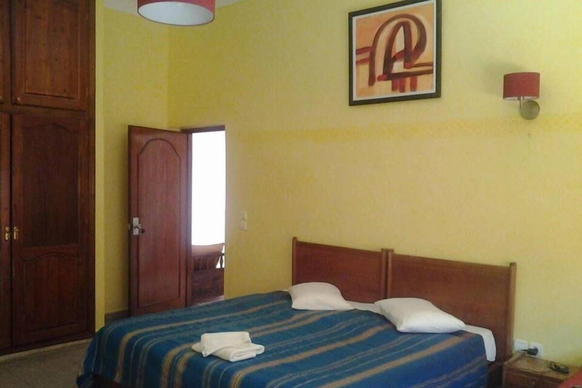 Ein Zimmer mit einem Bett, einem Holzschrank, einer Tür und einer Wandlampe.