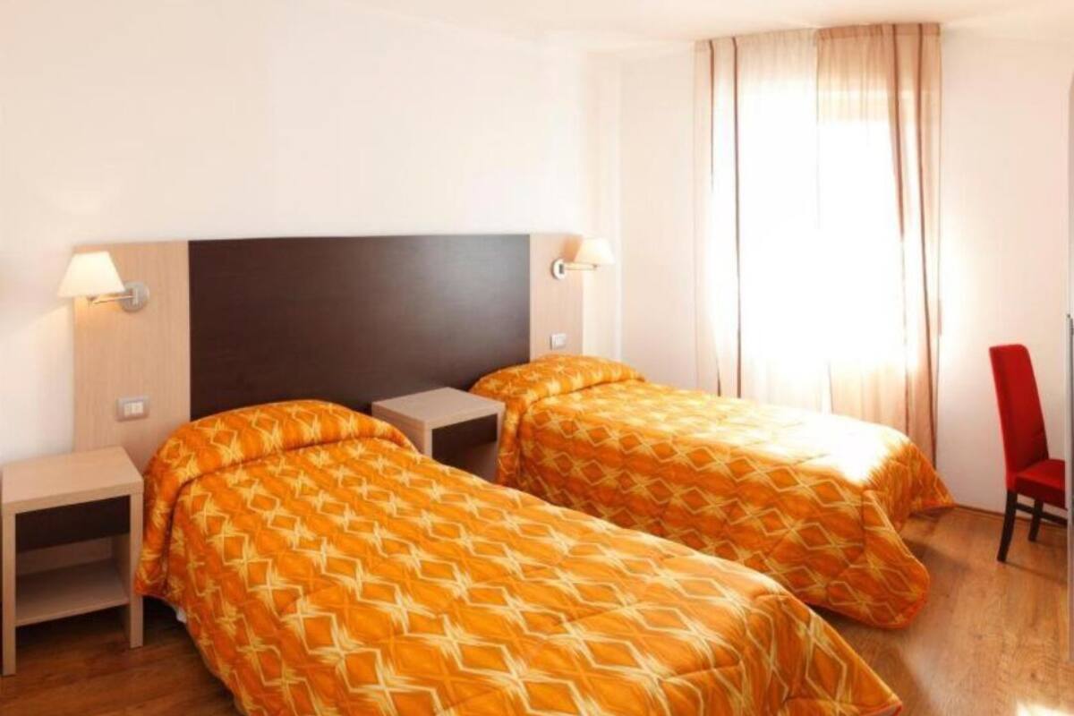 Ein Hotelzimmer mit zwei Betten, einem Schreibtisch und einem Stuhl.