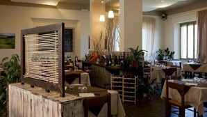 Een restaurant met houten tafels, stoelen en een bar voorzien van wijnflessen.