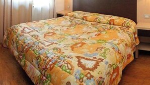 Een hotelkamer met een groot bed, een hoofdeinde, twee nachtkastjes en een raam met gordijnen.