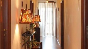 A hallway with wooden flooring, a table with a lamp, and a potted plant. - Hotel Garibaldi (San Quirico d'Orcia)