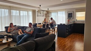 A modern living room with a sofa, a dining table, and a kitchen area.
