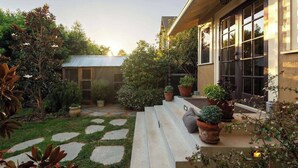 A well-maintained garden with stone pathways, potted plants, and a wooden bench. - B Street Historic House-Min to Convention Cnr, Gaslamp, Balboa-Comp. Bikes (San Diego)
