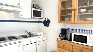 A compact kitchen with white cabinets, a stainless steel sink, a microwave, and a coffee maker. - Studio 1 room, sleeps 4, Saint Gilles Croix de Vie, Parking (Saint-Gilles-Croix-de-Vie)