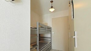 A small, clean room with a bunk bed, a door, and a light fixture. - Studio 1 room, sleeps 4, Saint Gilles Croix de Vie, Parking (Saint-Gilles-Croix-de-Vie)