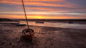 Ein Strand mit Booten und einem Sonnenuntergang.