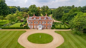 A large, historic building with symmetrical architecture, surrounded by well-maintained gardens and a central lawn. - Belchamp Hall Hayloft and Stables, Belchamp Walter (Belchamp Walter)