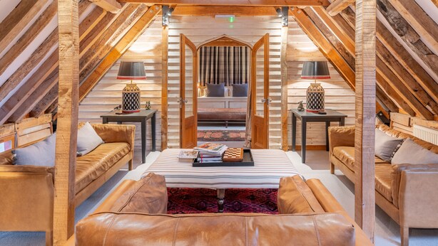 A cozy attic bedroom with a central bed, two side tables, and a leather bench. - Belchamp Hall Hayloft and Stables, Belchamp Walter (Belchamp Walter)