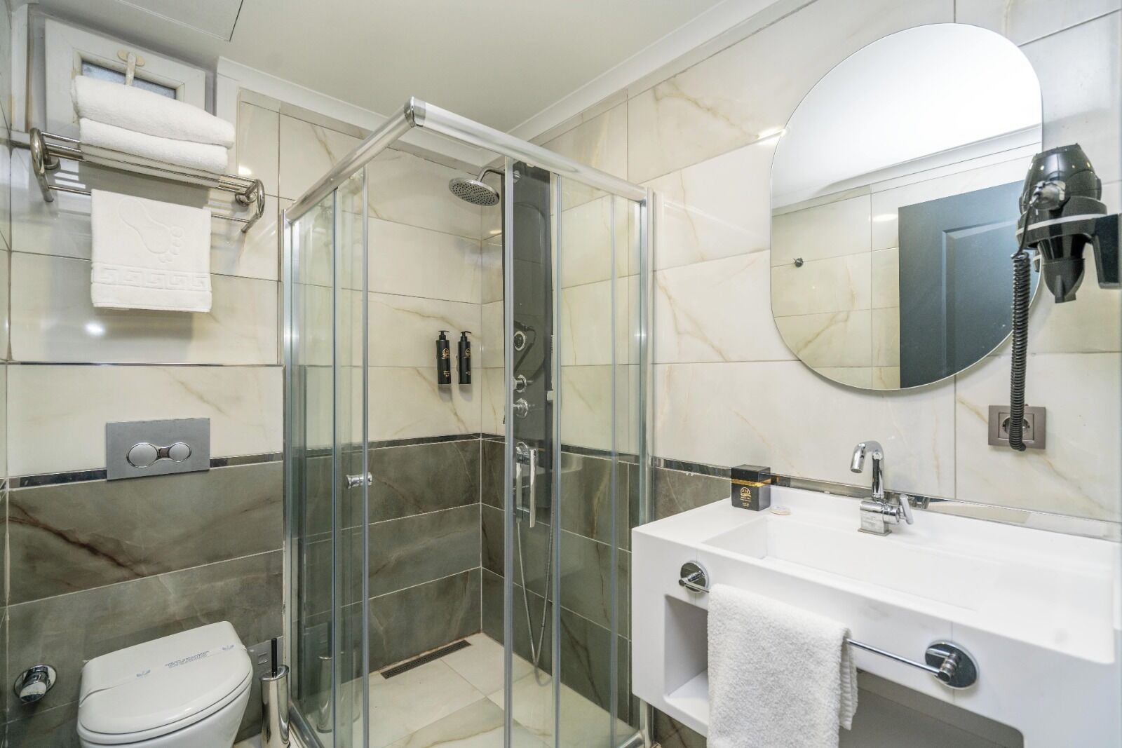 A modern bathroom with a glass-enclosed shower, a white sink, and a large mirror.
