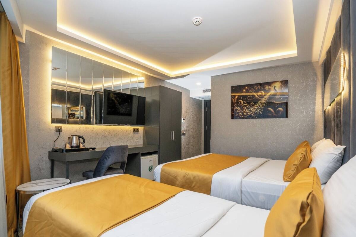 Ein Hotelzimmer mit zwei Betten, einem Schreibtisch, einem Stuhl, einem Fernseher und einem Bild an der Wand.