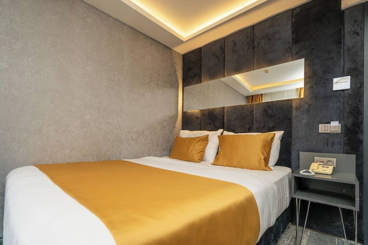 Ein Hotelzimmer mit einem großen Bett, einem Nachttisch, einem Spiegel und einer Wandleuchte.