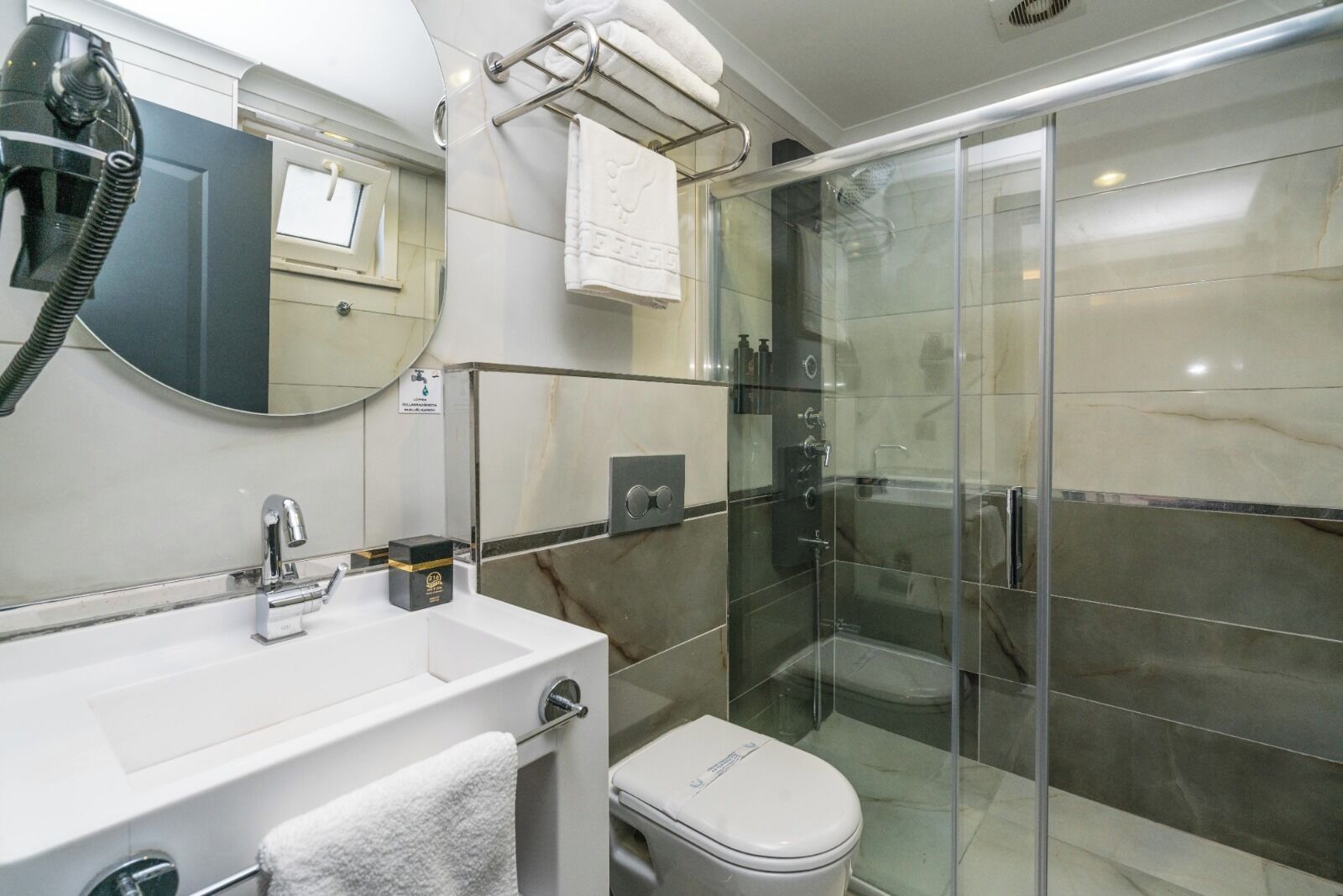 Un baño moderno con ducha acristalada, lavabo blanco y retrete.