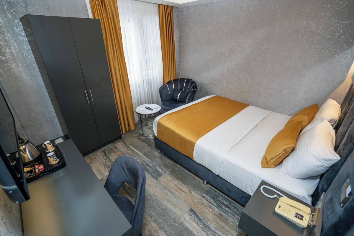 Ein Hotelzimmer mit einem Bett, einem Schreibtisch, einem Sessel, einem Kleiderschrank und einem Nachttisch mit Telefon.