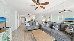 Ein Wohnzimmer mit grauem Sofa, einem Holztisch und Deckenventilatoren.