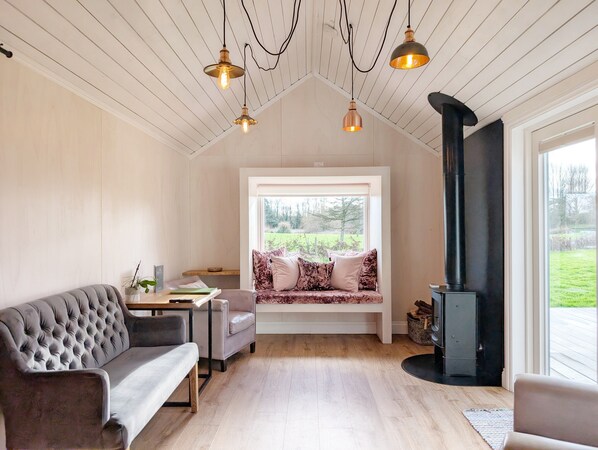 Relax in this inviting room with a high ceiling, sofa, and window seat offering a view of the outdoors.