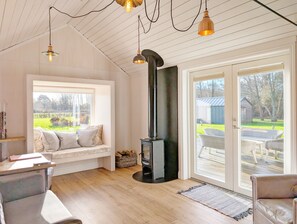 A cozy room with a built-in wood stove, a large window with a view of the outdoors, and a comfortable seating area.