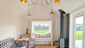 Una habitación acogedora con un sofá, un banco con cojines, una mesa y una chimenea.