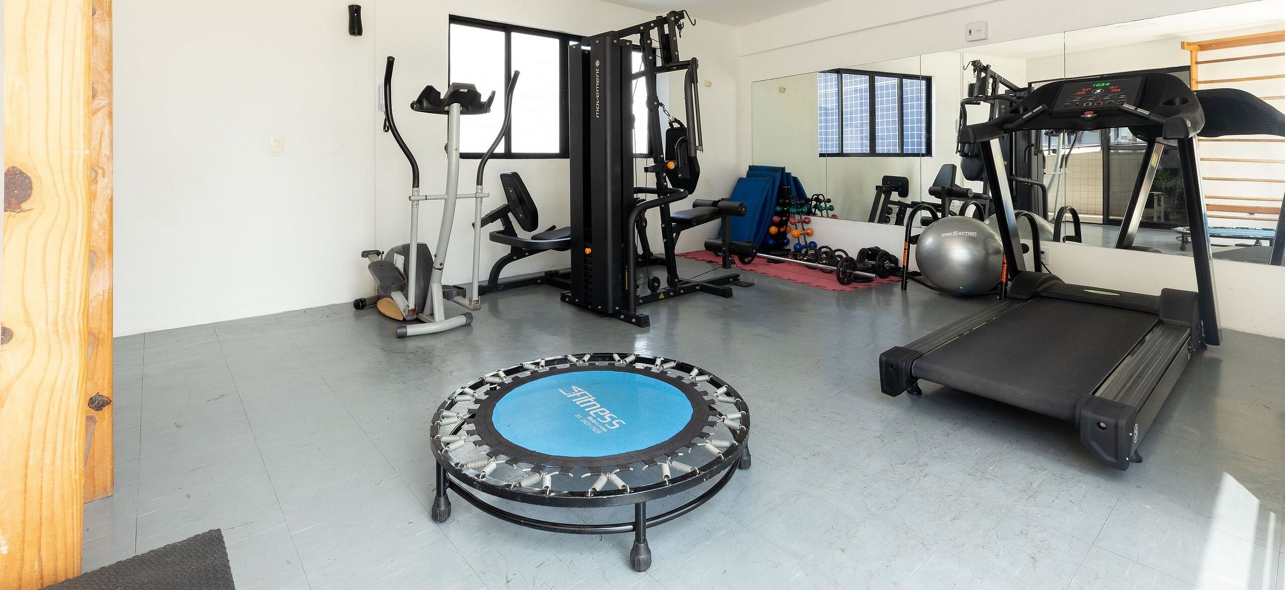 A gym with a treadmill, exercise bike, and various weights.
