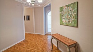 A hallway with wooden flooring, a bench, and a painting on the wall. - ELEGANT APARTMENT IN THE CENTER OF BARCELONA (Barcelona)
