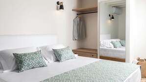 A modern bedroom with a large bed, a hanging light fixture, a wardrobe, and a mirror.