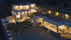 A modern two-story house with a patio area, outdoor seating, and a hot tub.