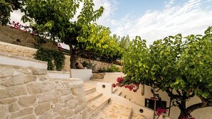 A stone staircase leading up to a building with a white facade and green foliage.