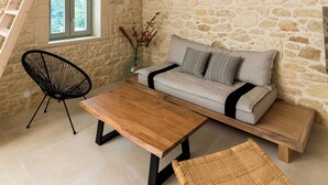 A rustic interior with a stone wall, wooden furniture, a lofted seating area, and a window with a view.