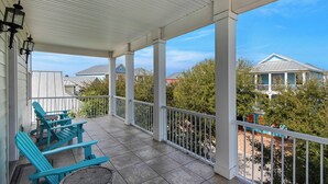 A covered porch with two Adirondack chairs, a small table, and a white railing. - 3300 sf! 3 Kings👑 Lagoon Pool-Villages of Crystal Beach-6BR Better Together☀️ (Destin)