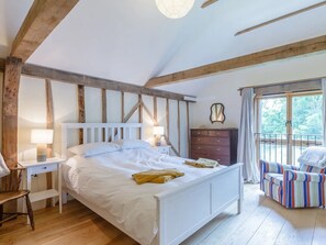 A bedroom with a wooden ceiling, a bed with white bedding, a dresser, a chair, and a window with curtains.