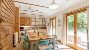 Une cuisine chaleureuse avec des meubles en bois, une table à manger avec des chaises et une grande fenêtre donnant sur un paysage verdoyant.