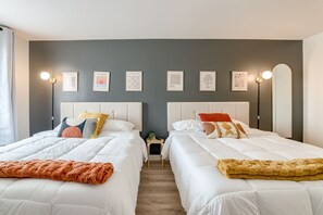Hotellihuone, jossa on kaksi sänkyä, pieni pöytä ja yöpöytä.