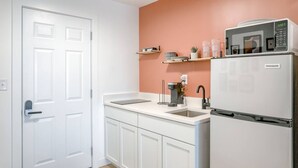 Een keuken met witte kastjes, een spoelbak, een koffiezetapparaat en een koelkast.