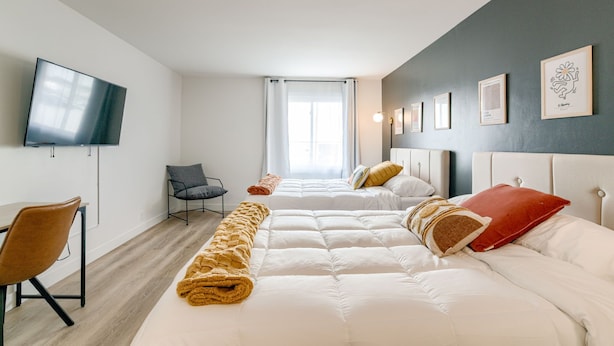 Ein modernes Hotelzimmer mit zwei Betten, einem Fernseher und Kunstwerken an den Wänden.