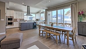 A modern kitchen with white cabinets, a central island, and a dining area with a wooden table and benches. - 25%Off Sept 17-19 Walk 2 Beach, Amazing Ocean View (Ventura)