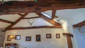 A rustic interior with exposed wooden beams, a stone wall, and framed pictures on the wall.