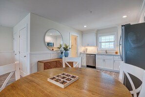 A modern kitchen with white cabinetry, a wooden dining table, and a large mirror. - 3005 Queen Suite, 3rd Floor Surfside (Surf City)