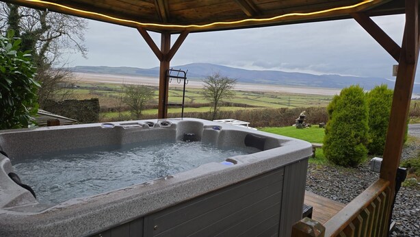 A hot tub with a view of a rural landscape, including fields and distant mountains. - Haven Lodge Kirkby In Furness -  a lodge that sleeps 2 guests  in 1 bedroom (Kirkby in Furness)
