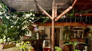 Une personne tenant un verre de vin rouge dans un bain à remous, sous une pergola en bois.