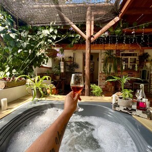 A person holding a glass of red wine in a hot tub with a wooden pergola overhead. - Ecohotel Zona 7 (Rionegro)