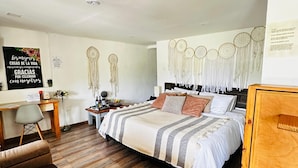 A bedroom with a bed, a desk, a chair, and a bedside table.