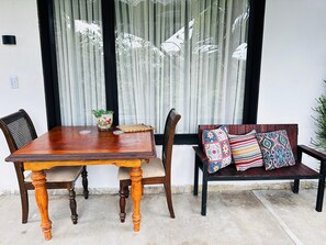 A wooden dining table with chairs and a bench with colorful cushions. - Ecohotel Zona 7 (Rionegro)