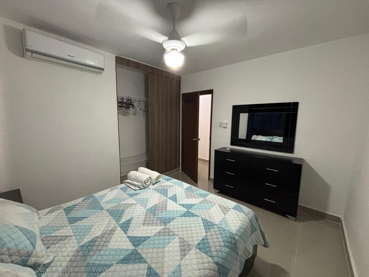 Une chambre à coucher comprenant un lit, une commode, un miroir et un appareil de climatisation.