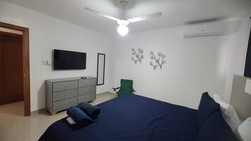 A bedroom with a bed, a dresser, a TV, a ceiling fan, and wall decorations.